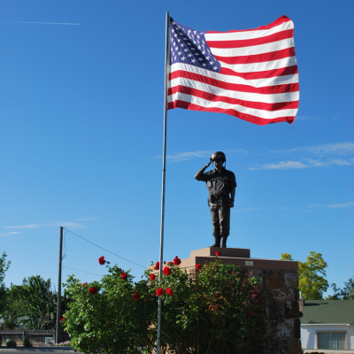 Flagpole and memorial statue of a soldier saluting.