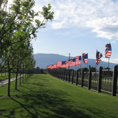 View of the walkway with green grass and US flags on the fence.